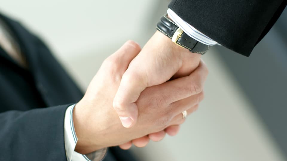Zwei Geschäftsmänner reichen sich die Hände (Symbolbild).