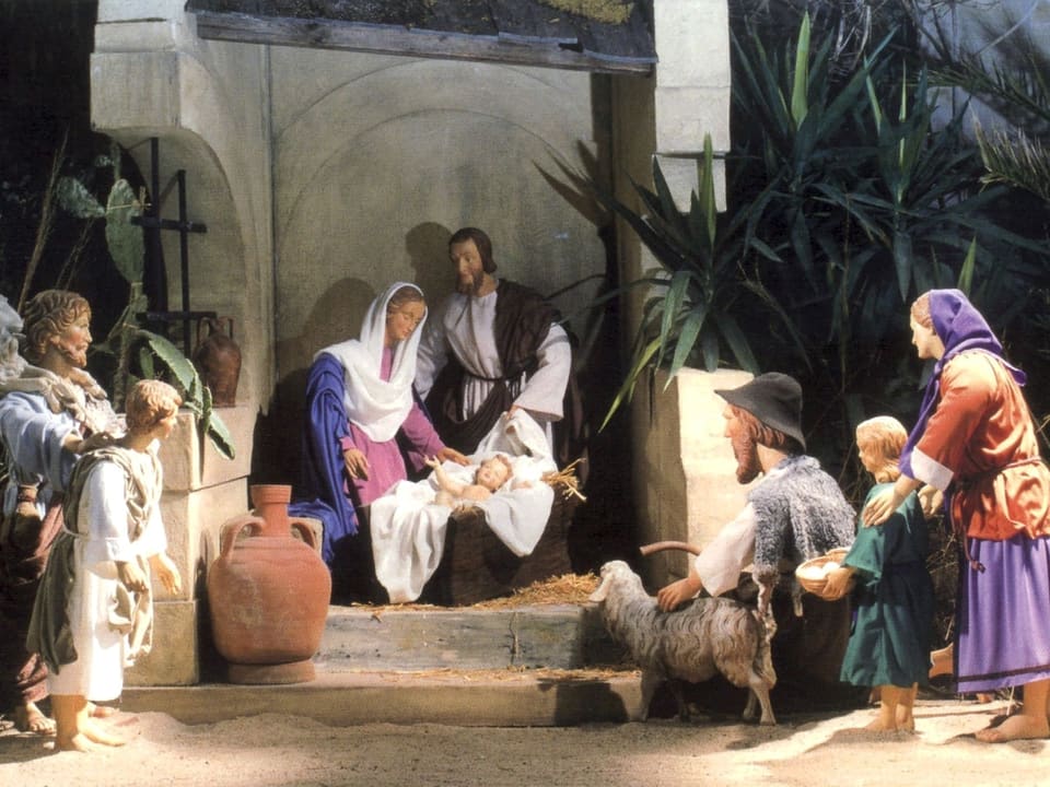 Ein Krippenbild mit Maria, Joseph und dem Christkind in der Mitte.