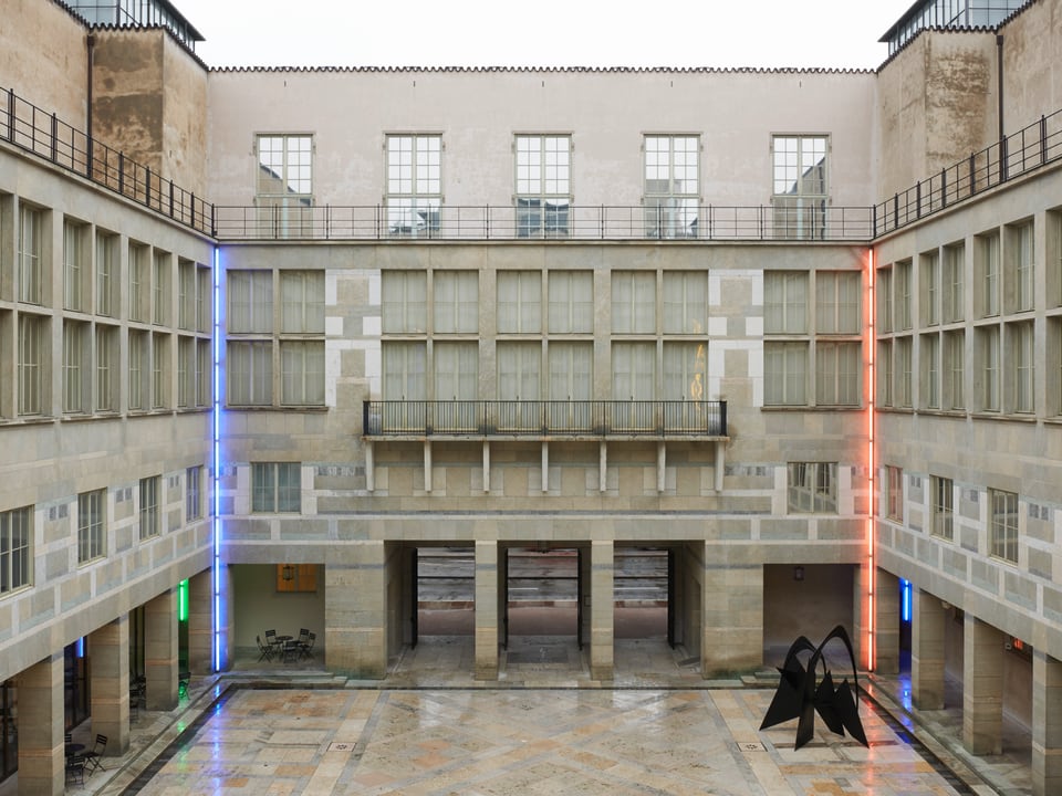 Innenhof des Kunstmuseums Basel. An den hinteren beiden Ecken des Innenhof sind am Gebäude eine rote und eine blaue Neonröhre befestigt.