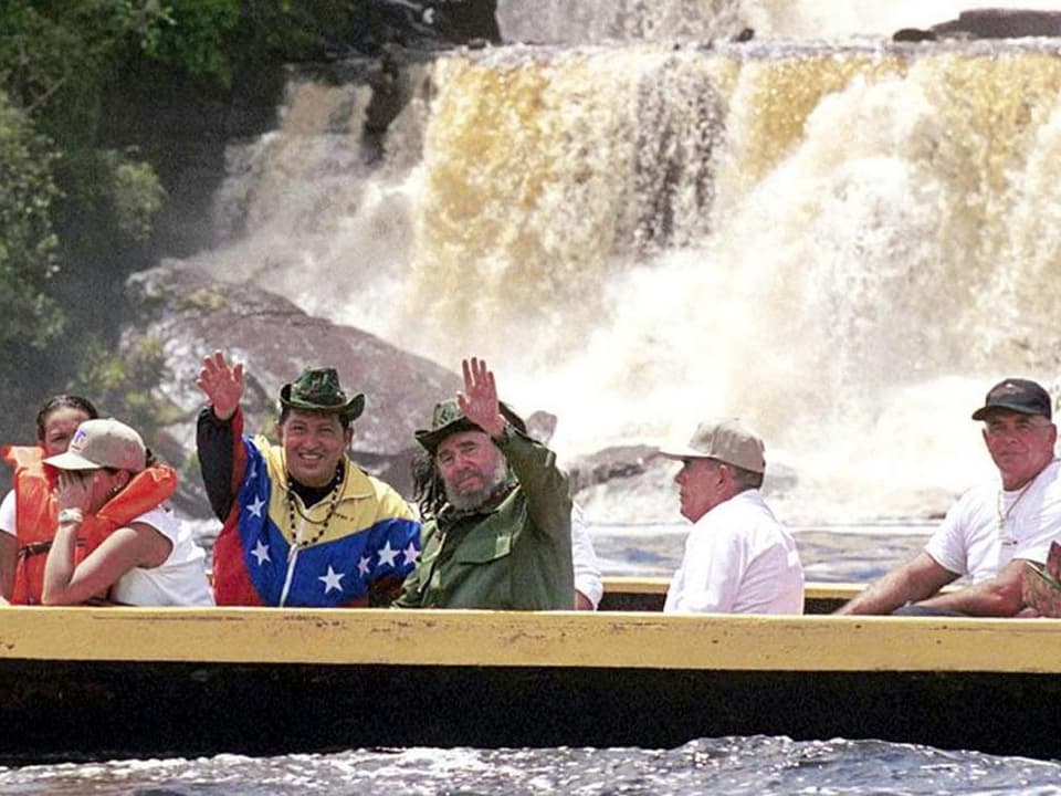 Chàvez und Castro winken aus einem Boot