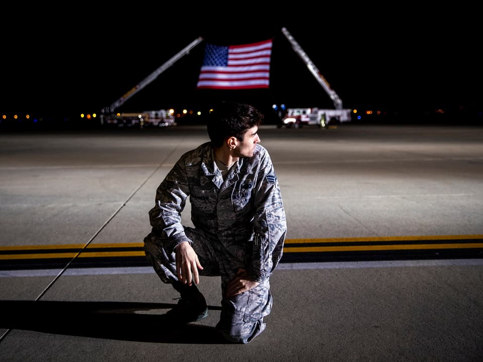 Ein Soldat vor einer grossen US-Flagge.
