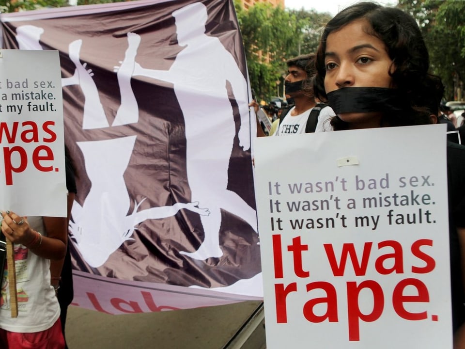 Eine Frau mit einem Band über dem Mund hält ein Plakat: «Es war nicht schlechter Sex. Es war nicht ein Fehler. Es war nicht mein Fehler. Sondern eine Vergewaltigung.»
