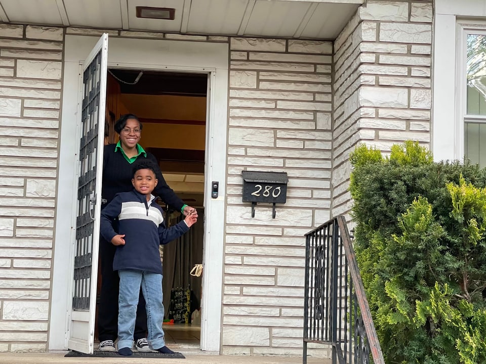 Mutter und Sohn stehen im Eingang ihres Hauses.