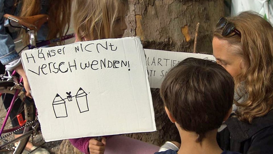 Protestierende mit einem Plakat: Häuser nicht verschwenden.