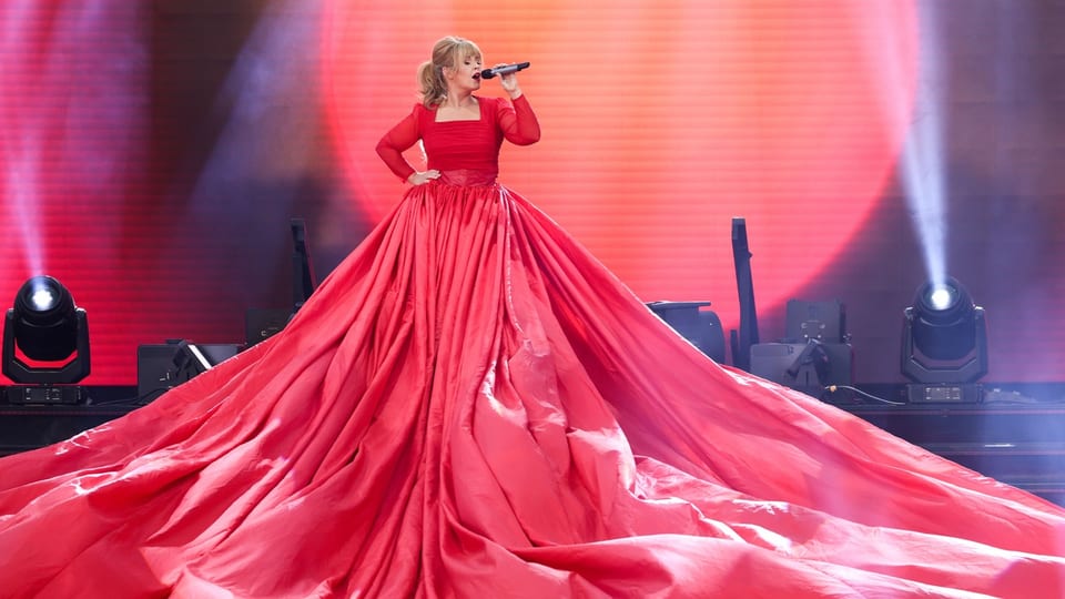 Maite Kelly mit überdimensionalem roten Kleid auf Bühne. 