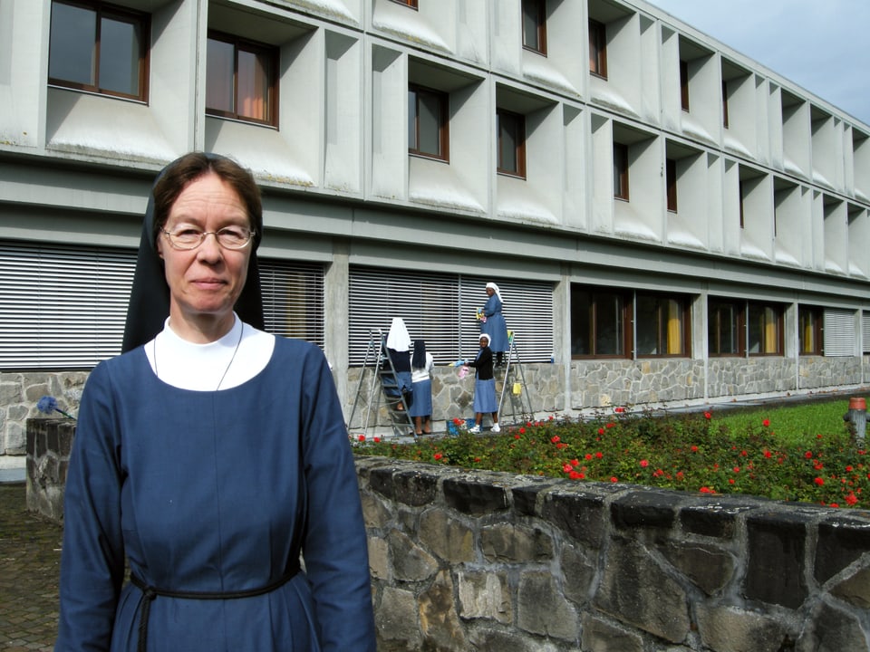 Eine Nonne steht vor dem Klostergebäude.