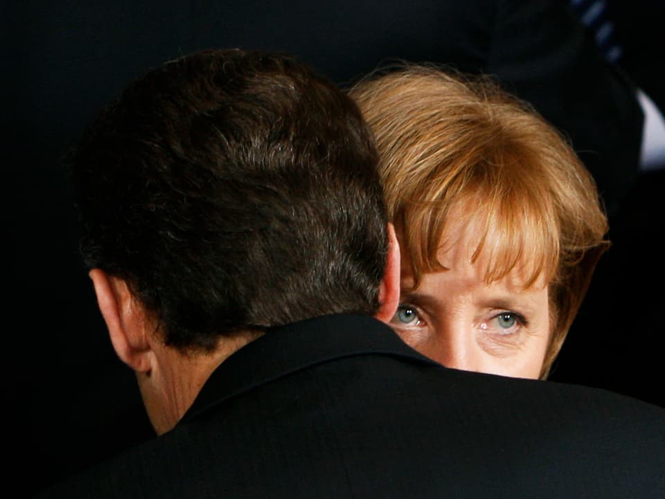 Germany's Chancellor Angela Merkel (R) talks with France's President Nicolas Sarkozy during a family photo session at a EU summit in Brussels March 13, 2008. European Union leaders meet on Thursday for a two-day summit to set a tight timetable for adopting ambitious energy policy reforms and measures to fight climate change, despite some sharp differences over how to achieve those goals.