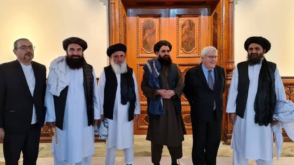 Sechs Männer, vier davon in Talibankleidung, zwei in Anzügen, posieren nach einem Treffen.