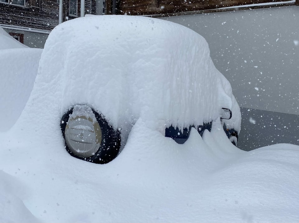 Ein Auto dass unter dem Schnee kaum zu erkennen ist.
