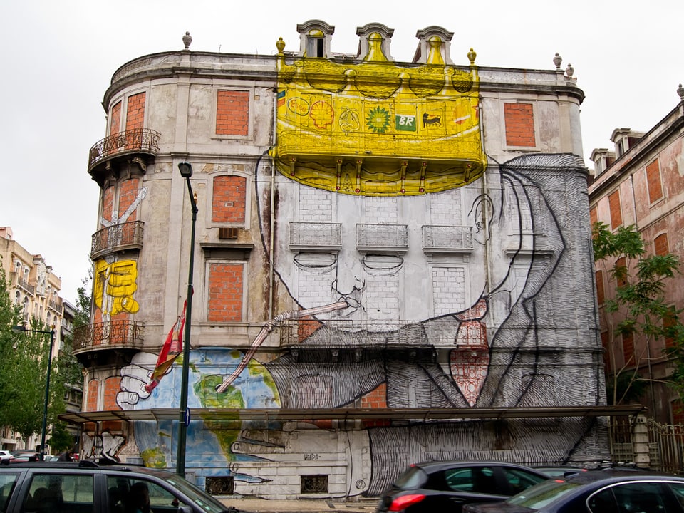 Graffito auf einem Haus in Lissabon: Ein Geschäftsmann, bekrönt mit den Emblemen internationaler Ölkonzerne, saugt die Erde mit einem Strohhalm aus. 