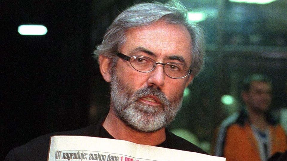 Der ermordete Journalist Slavko Ćuruvija hält eine Zeitung in der Hand.