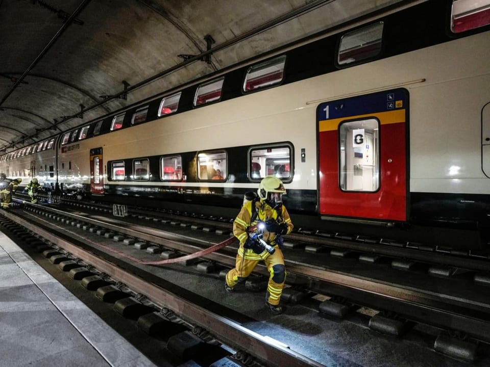Feuerwehrmann mit Schlauch vor Zug.