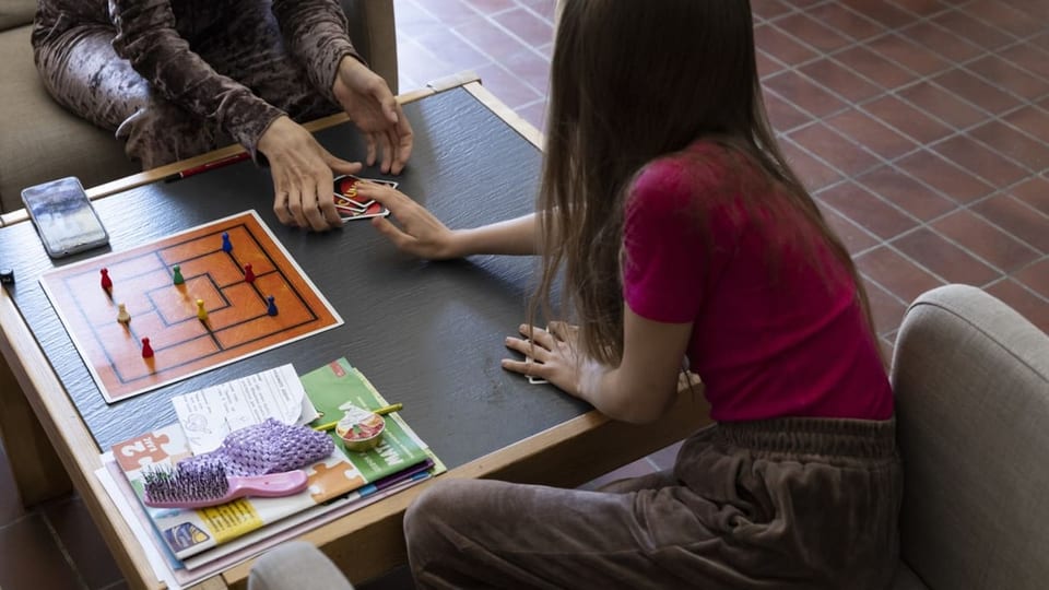 Kind und Erwachsene spielen ein Brettspiel