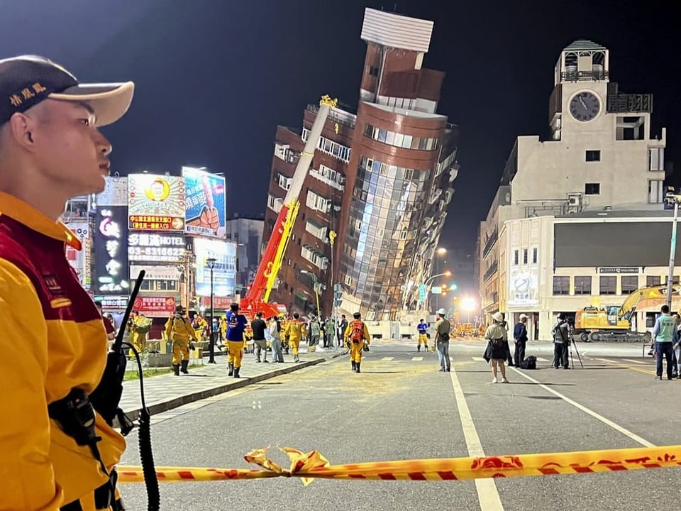 Ein Rettungshelfer steht in der Nähe der abgesperrten Stelle eines schiefen Gebäudes nach dem Erdbeben in Hualien.