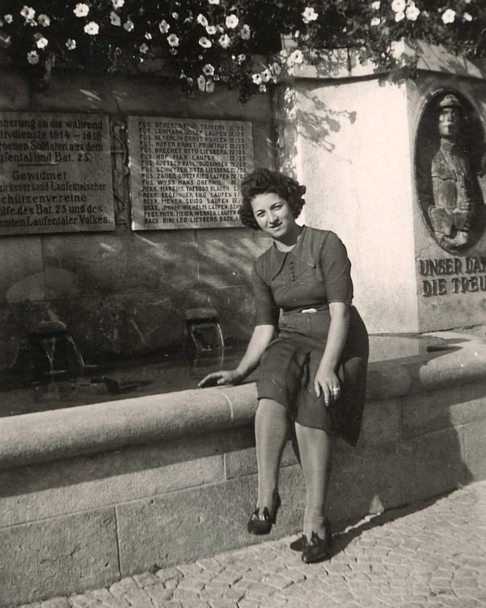 Die junge Frau sitzt auf dem Rand eines grossen Brunnens.