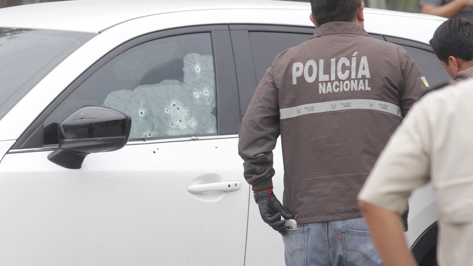 Das Auto des Staatsanwaltes Suarez mit mehreren Einschusslöchern. Davor steht ein Polizeibeamter.