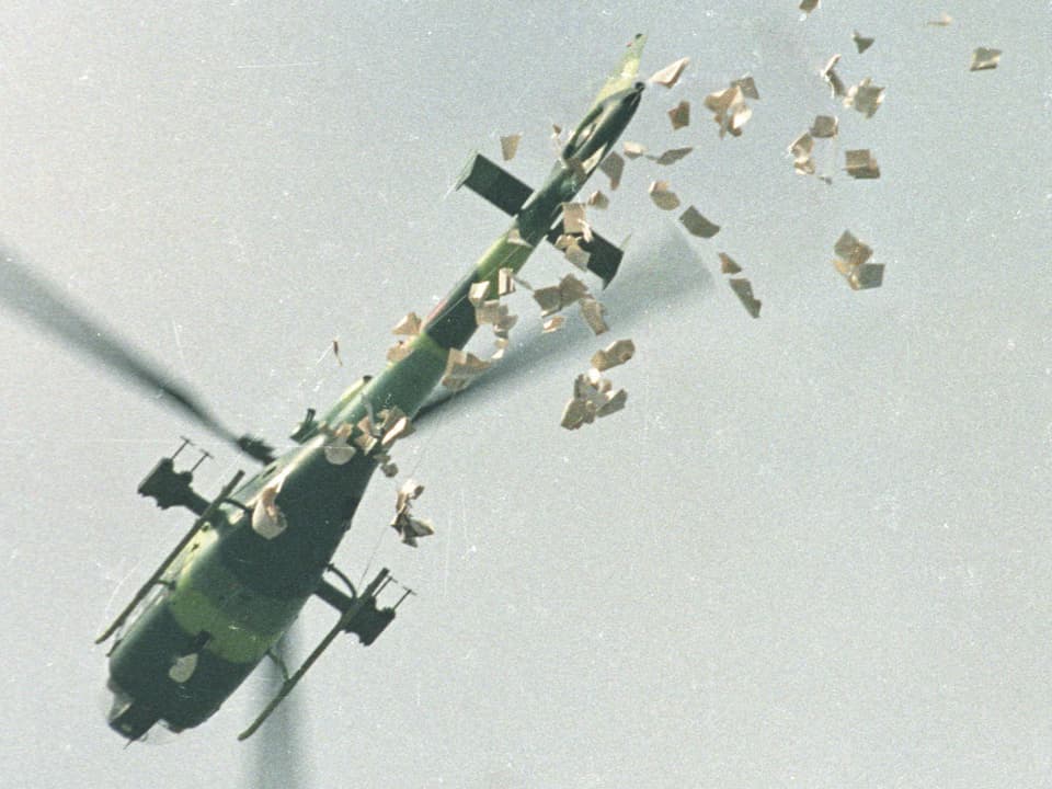 Ein Helikopter wirft Flugblätter ab.