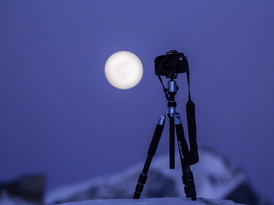 Kamera, die auf den violetten Nachthimmel gerichtet ist. In der Mitte der volle Mond. 