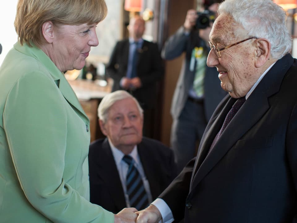 Angela Merkel schüttelt Henry Kissinger die Hand