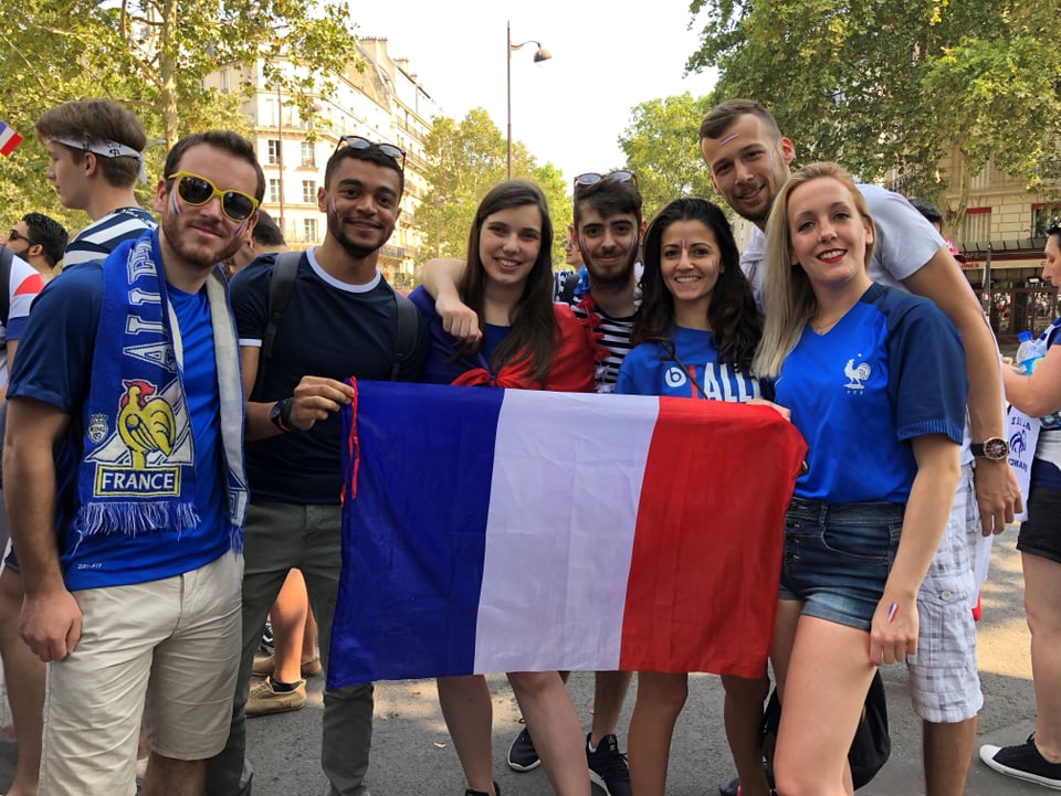 Fans halten eine Frankreich-Flagge in den Händen und posieren.