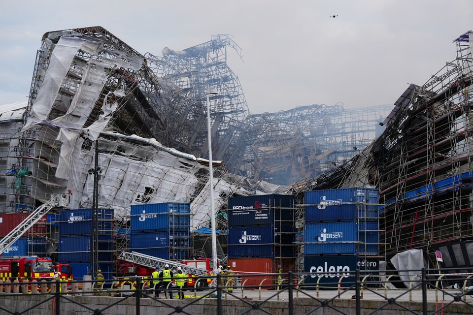 Zusammengestürztes Gebäude mit Gerüsten und Feuerwehrautos davor