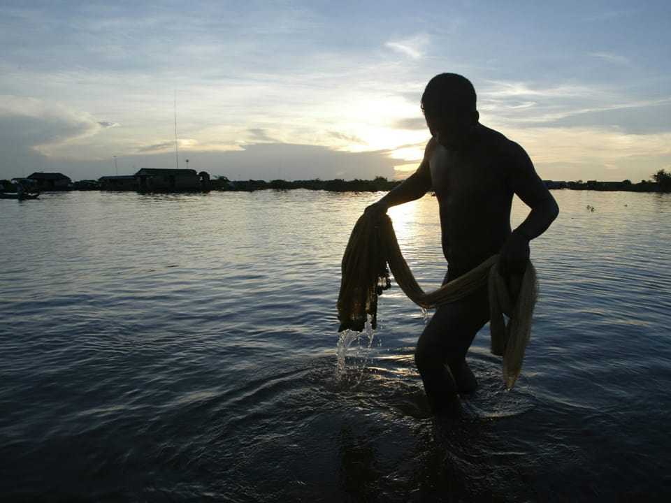 Mann mit Fisch an der Leine im See
