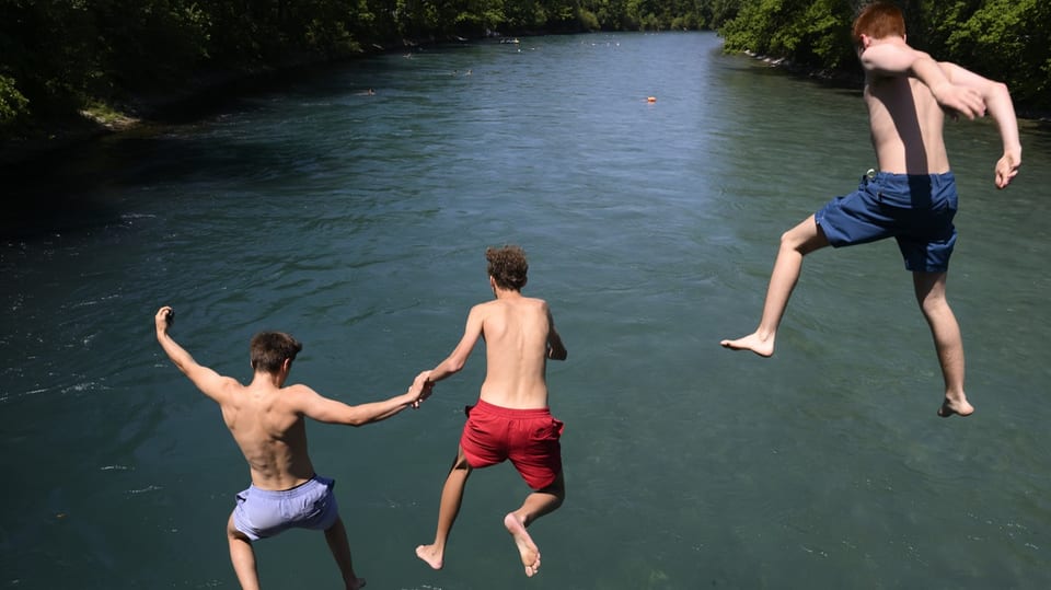 Drei Jugendliche springen in einen Fluss