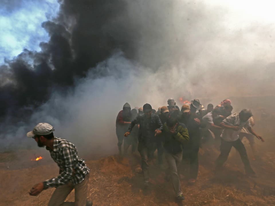 Eine Gruppe von Demonstranten versucht den Tränengas-Wolken zu entkommen.