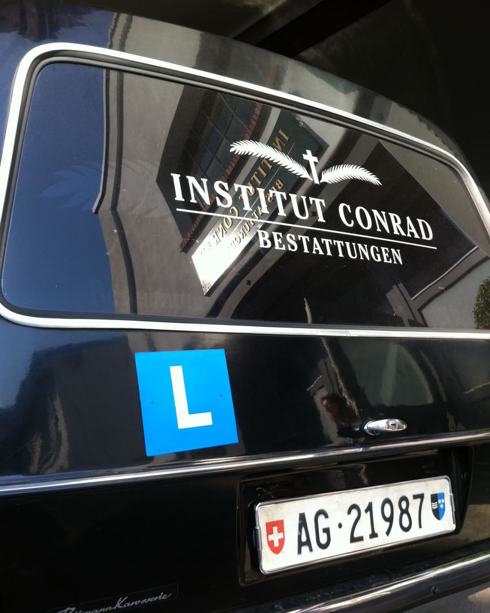 Ein Leichenwagen ist mit einem blauen L als Lernfahrzeug gekennzeichnet,