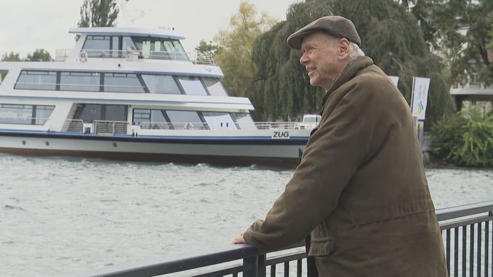 Rentner Michel Mortier steht am Geländer am Ufer des Zugersees und blickt auf den See hinaus. 
