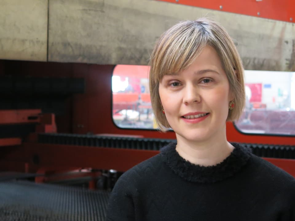 Anna Aebischer in der Produktionshalle vor einer Lasermachine.