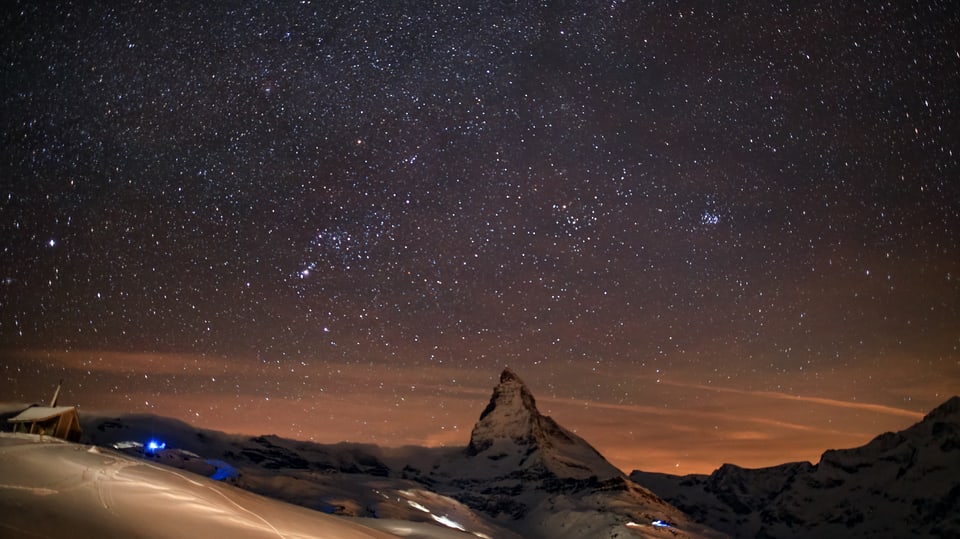 Ein Sternenhimmel hoch über Zermatt und dem Matterhorn. Abertausende kleine Punke leuchten.