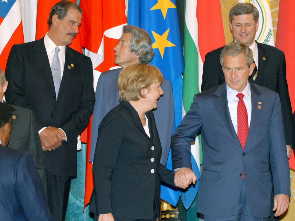 Bush und Merkel halten sich in St. Petersburg 2006 an der Hand.