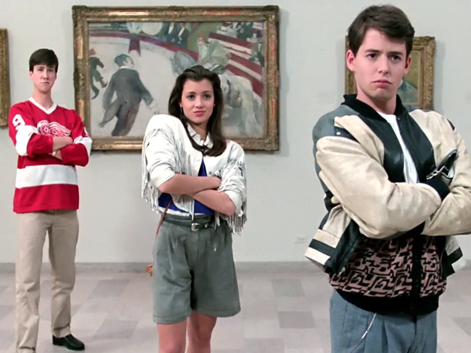 Drei Schüler stehen, die Arme verschränkt, in einem Museum.