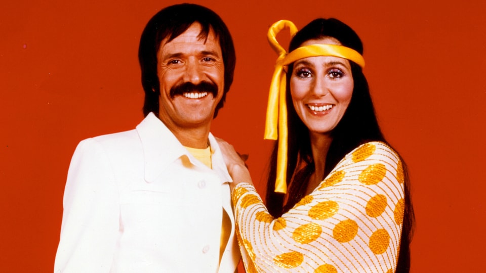 Cher posiert mit gelben Stirnband un damaligen Ehemann Sonny Bono.