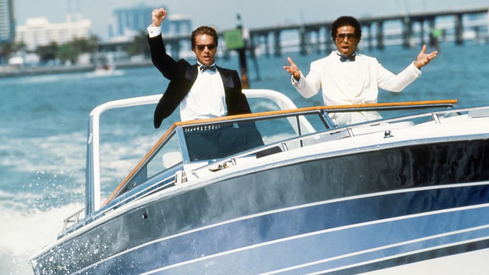 Still aus «Miami Vice»: Don Johnson und Philip Michael Thomas fahren in Anzüge gekleidet auf einem Schnell-Boot.