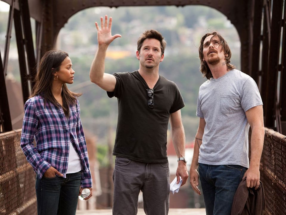 Auf einer Brücke stehen Zoë Saldaña, Scott Cooper und Christian Bale (von links).