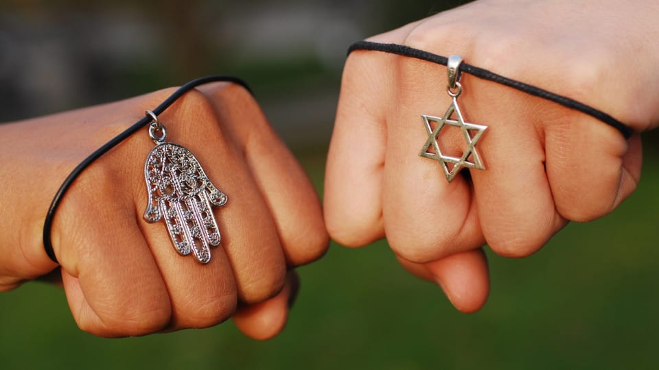 Zwei Hände zeigen die religiösen Symbole Hand der Fatima und Davidstern.