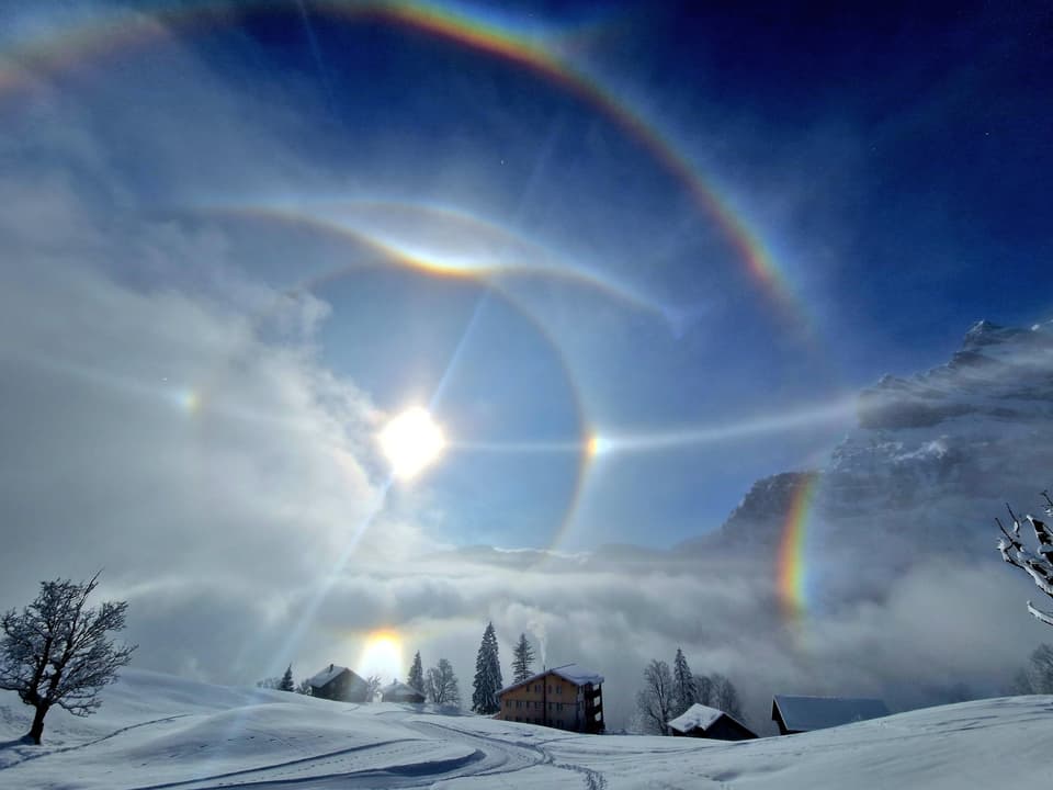 Verschneite Bergwelt mit Nebelschwaden, blauem Himmel und Sonne mit verschiedenen Lichteffekten. 