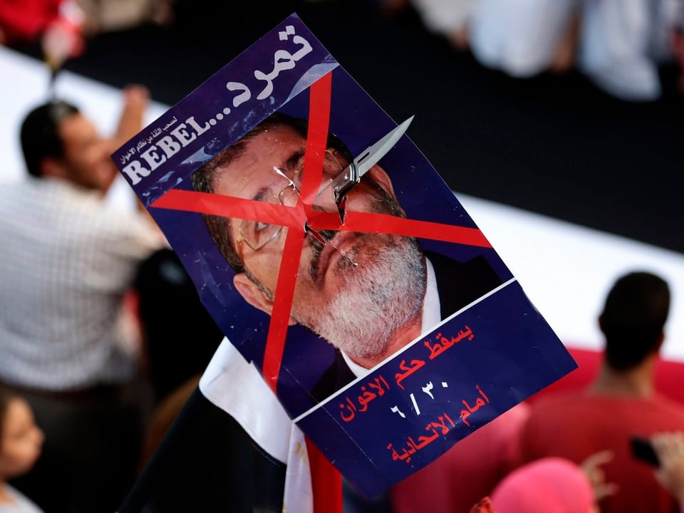 Ein Plakat mit Portrait von Mursi, über seinem Gesicht prangt ein grosses rotes Kreuz.