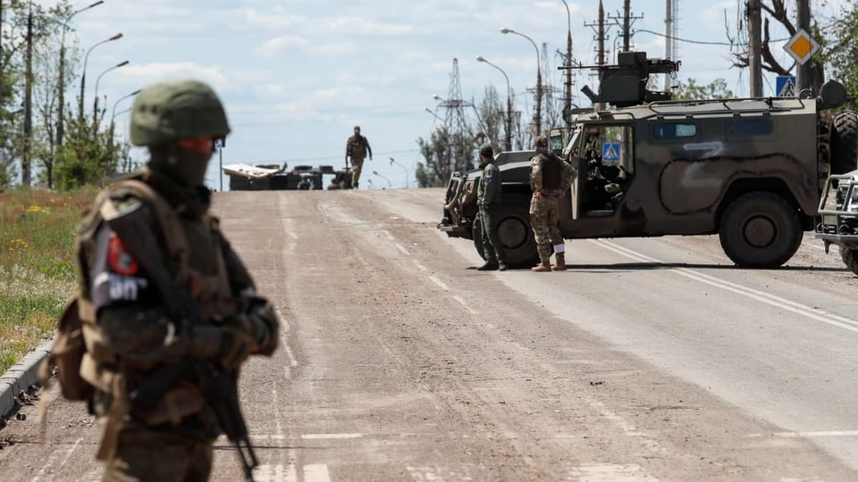 Mehrere russische Soldaten und ein Panzer stehen auf einer Strasse in Mariupol.
