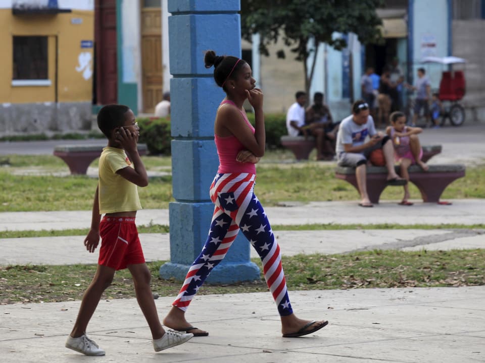 Zwei kubanische Teenager unterwegs, ein Junge und ein Mädchen. Das Mädchen trägt Hosen, welche in den Farben der amerikanischen Flagge gehalten sind
