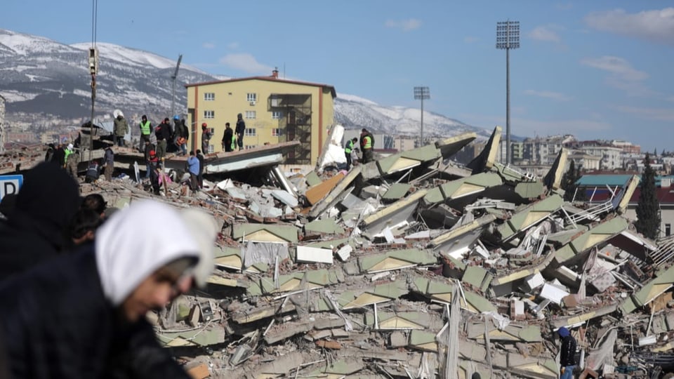 Menschen stehen auf Trümmern nach dem Erdbeben.