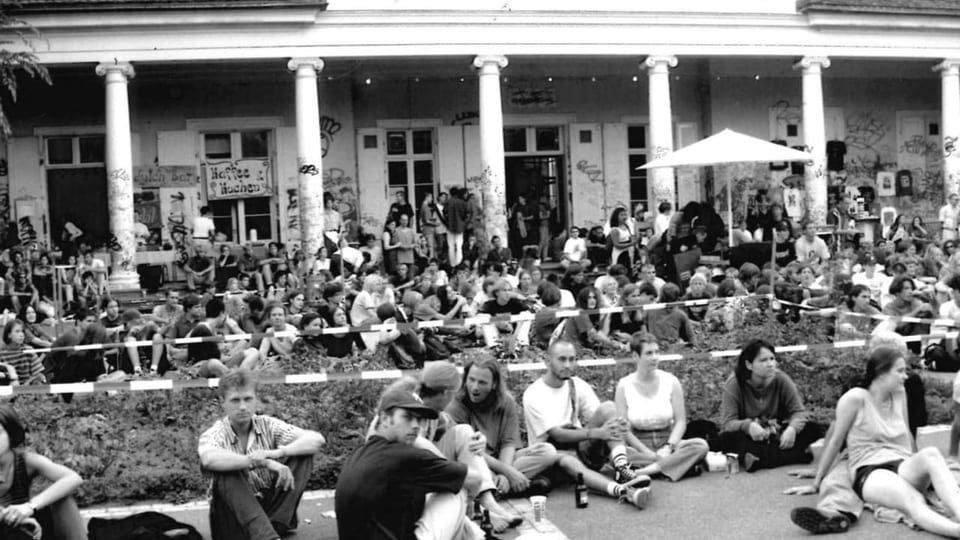 Eine grosse Gruppe Jugendliche sitzt vor dem Basler Sommercasino.