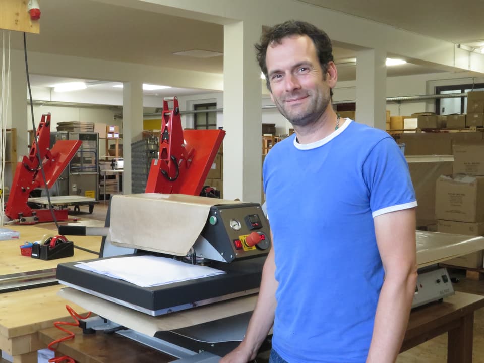 Patrick Allemann steht vor einer Druckmaschine für T-Shirts in der Fotoblitz AG Aarwangen.