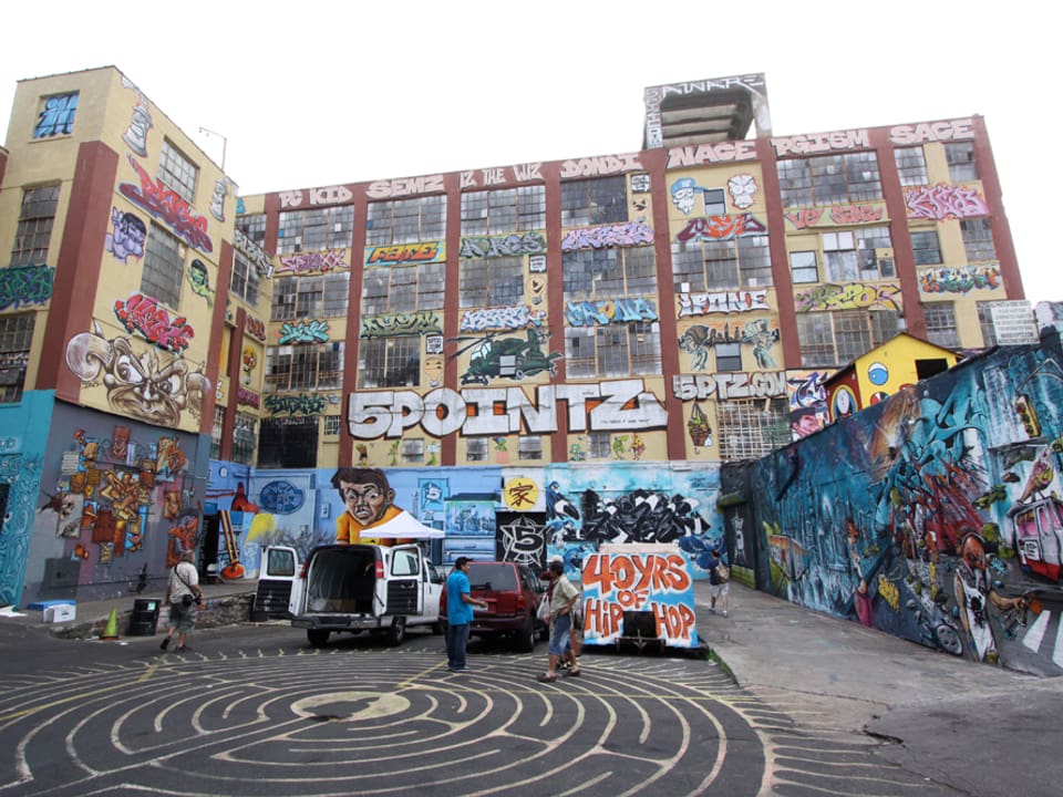 Ansicht des alten Fabrikgebäudes, komplett mit bunten Graffitis bedeckt.