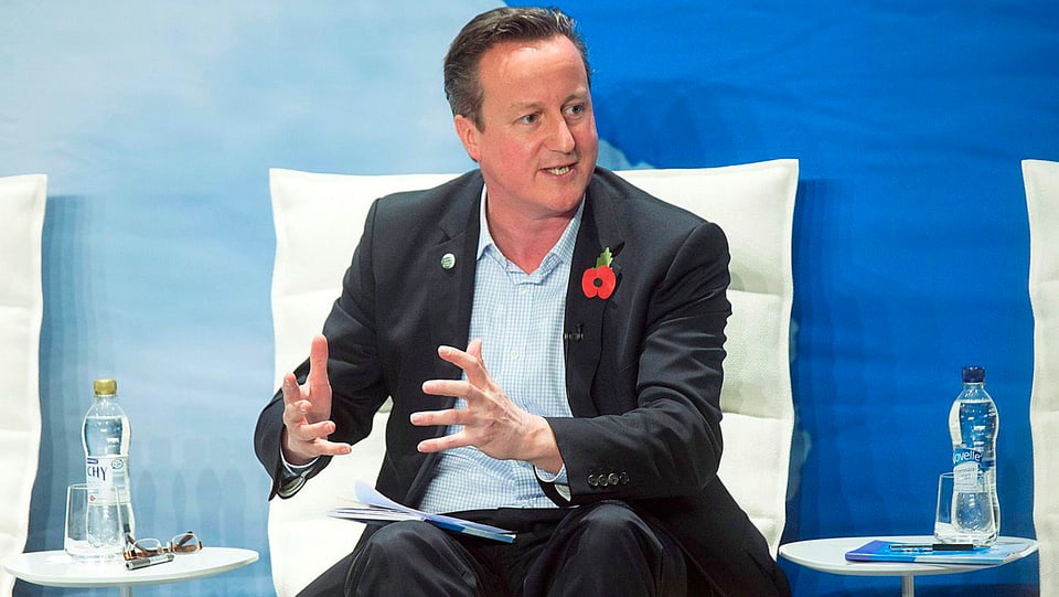David Cameron, auf Sessel sitzend und mit den Händen gestikulierend.
