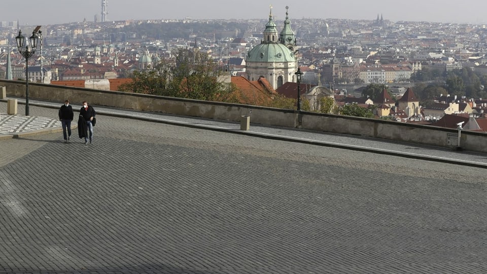 Die Plätze sind leer: zwei Menschen laufen über den sonst vollen Platz vor dem Prager Schloss.