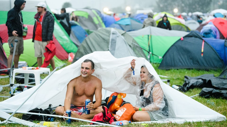 Menschen in Zelt unter Regen.