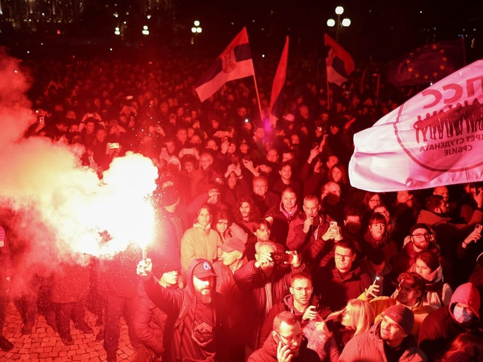 Menschen protestieren mit Fahnen und Petarden in Belgrad.
